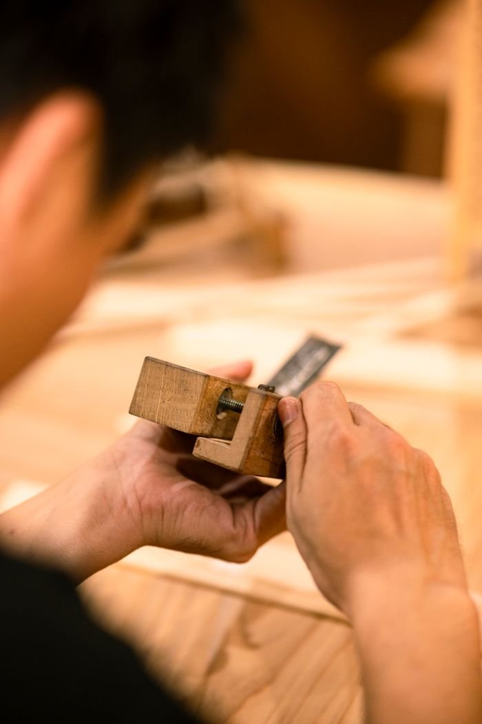 Close-up of a craftsperson skillfully working with a handheld woodworking tool.